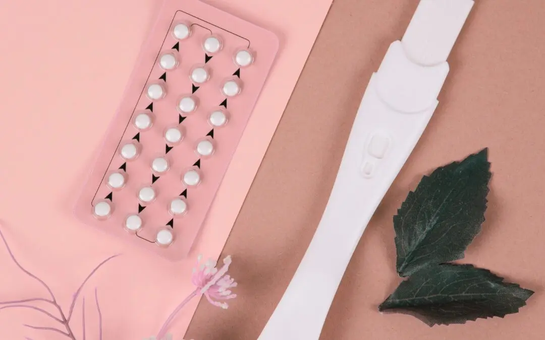 birth control and pregnancy test on pink table
