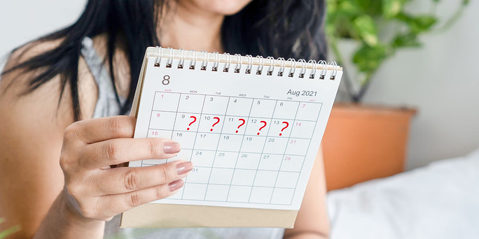 Woman looking and a calendar wondering "can you get pregnant on your period?"
